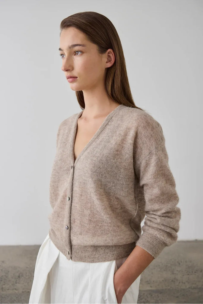 Woman wearing a beige cardigan over a white top. Laing Fine Alpaca Cardigan in Hazel.