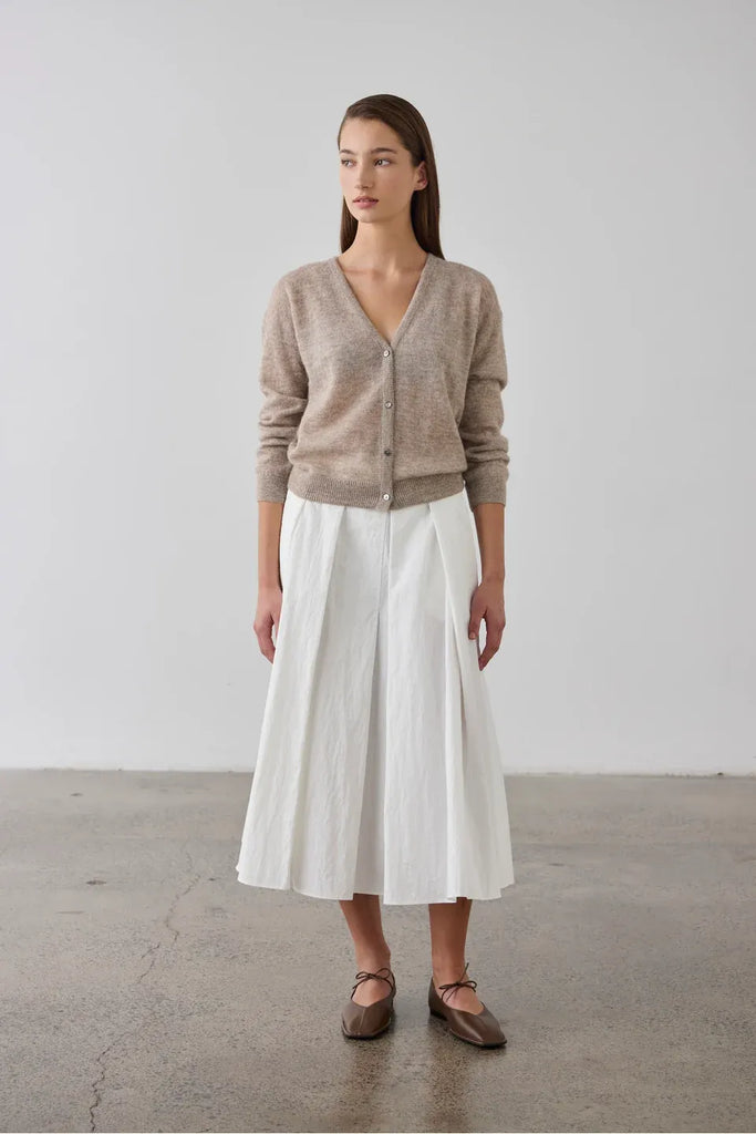 Woman wearing a beige cardigan over a white top. Laing Fine Alpaca Cardigan in Hazel.