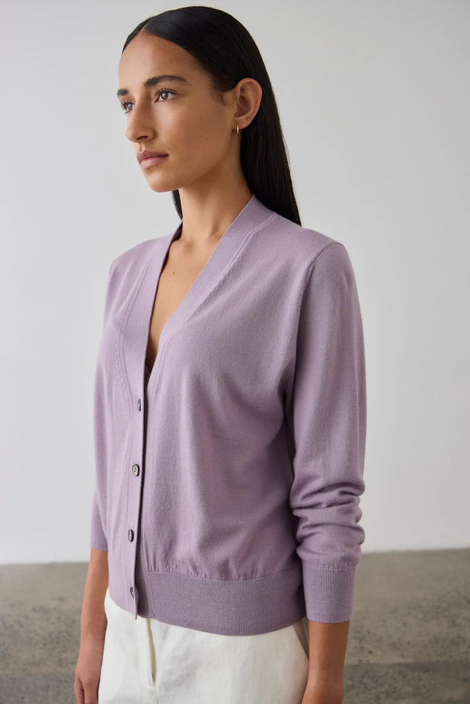 Woman wearing a light purple cardigan. Laing Merino V Neck Cardigan in Iris.