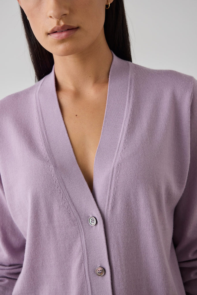 Woman wearing a light purple cardigan. Laing Merino V Neck Cardigan in Iris.