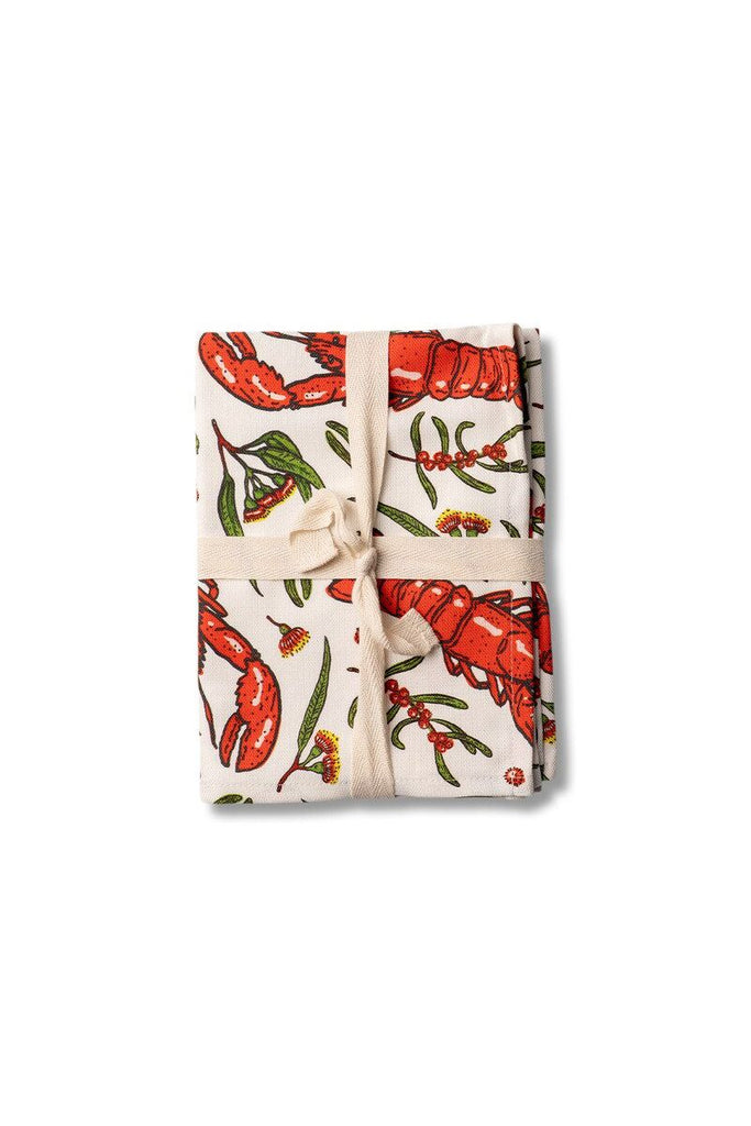 Studio Milligram Folded tea towel with a lobster pattern tied with a ribbon on a white background.