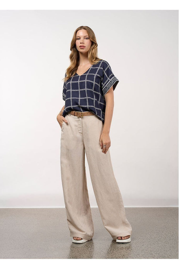 Woman wearing a blue checkered top and beige pants against a white background, Loobies Story Lyrical Top
