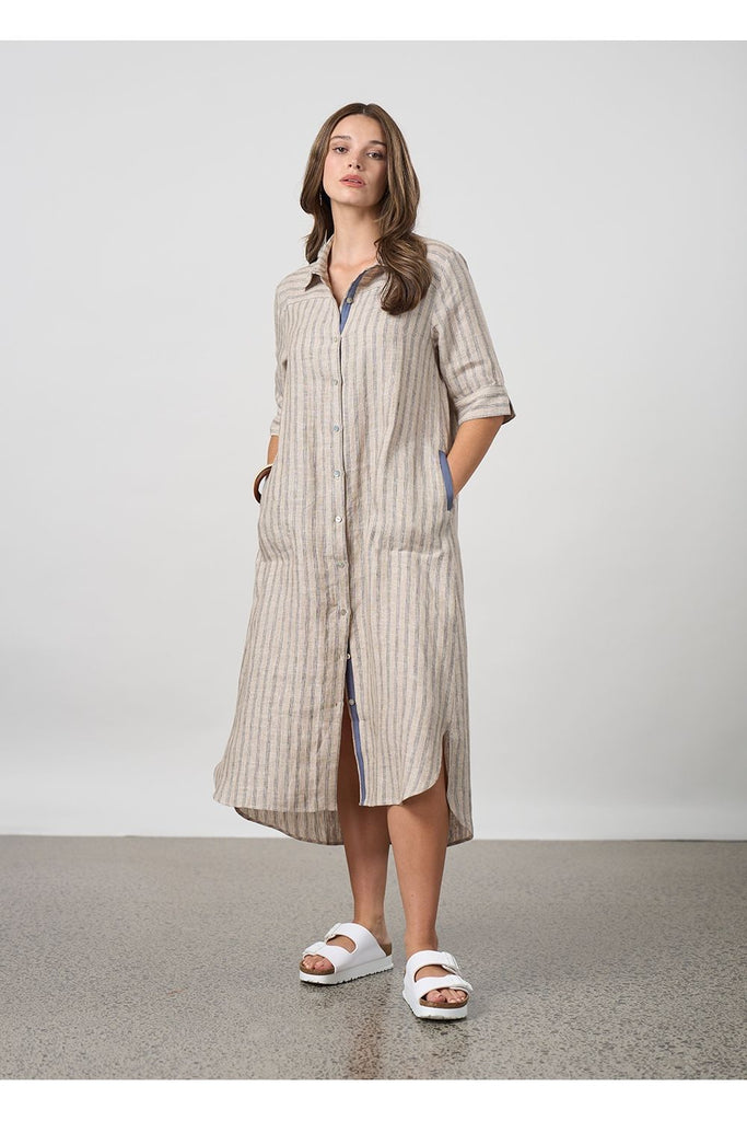 Woman wearing a long striped beige shirt dress on a plain background. Madly Sweetly Interval Shirt dress in pumice.