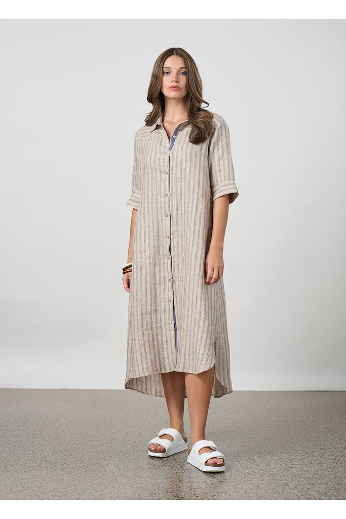Woman wearing a long striped beige shirt dress on a plain background. Madly Sweetly Interval Shirt dress in pumice.