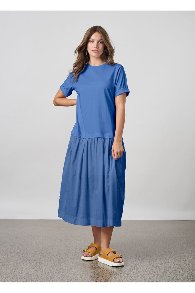 Woman wearing a blue dress standing against a plain background. Madly Sweetly Gossamer dress in Lake Blue.
