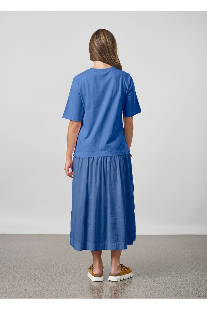 Woman wearing a blue dress standing against a plain background. Madly Sweetly Gossamer dress in Lake Blue.