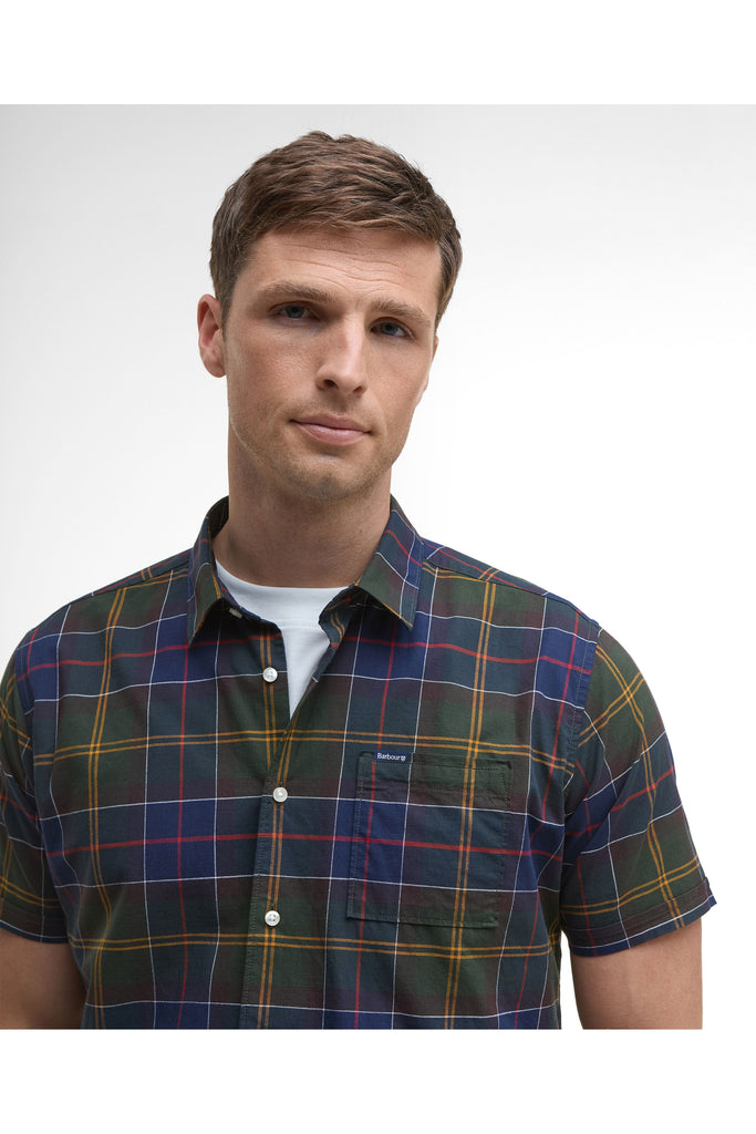 Man wearing a plaid shirt and beige pants on a white background. Barbour Gordon Summer Shirt in Classic Tartan.