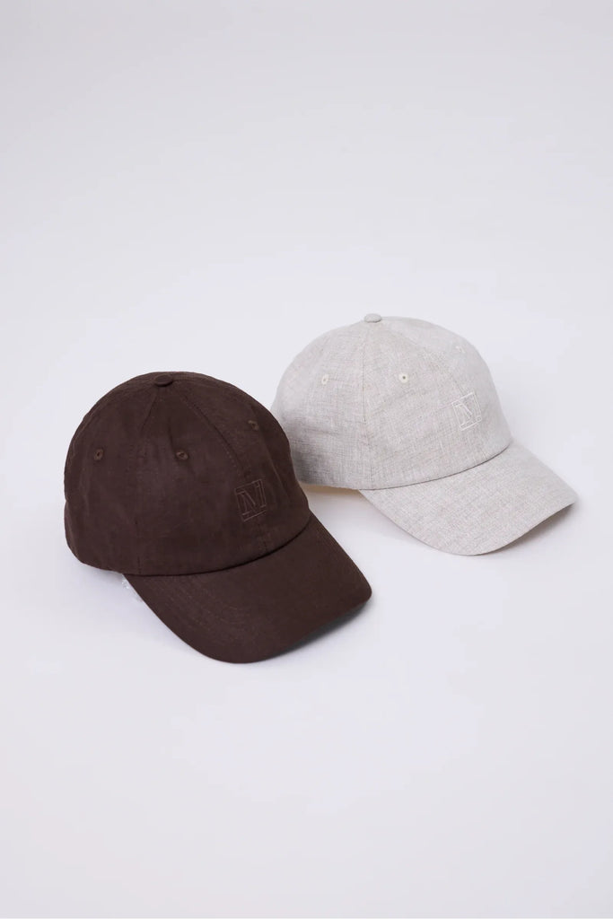 Two baseball caps, one brown and one beige, on a white background.  Marlow Icon Linen Cap in carob or natural.