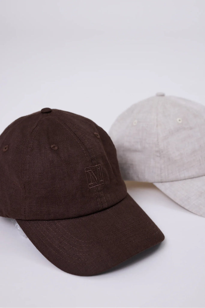 Two caps, one brown and one beige, on a white background.  Marlow Icon Linen Cap in carob or natural.