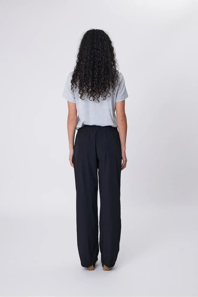 Woman wearing a gray shirt and black pants on a white background. Marlow Intrepid Pant 2.0 in Black