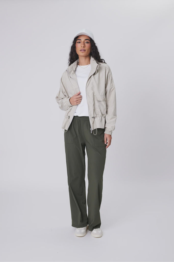 Person wearing a beige jacket and green pants on a white background. Marlow Intrepid Pant 2.0 Olive.