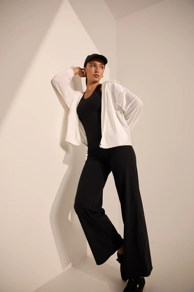 Person wearing a white windbreaker on a plain background. Motion Windbreaker in white from Marlow.