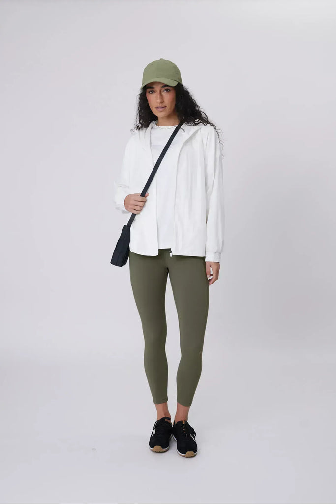 Person wearing a white windbreaker on a plain background. Motion Windbreaker in white from Marlow.