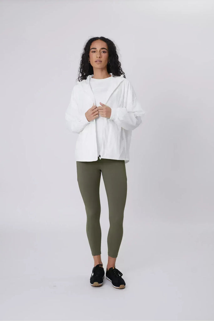 Person wearing a white windbreaker on a plain background. Motion Windbreaker in white from Marlow.
