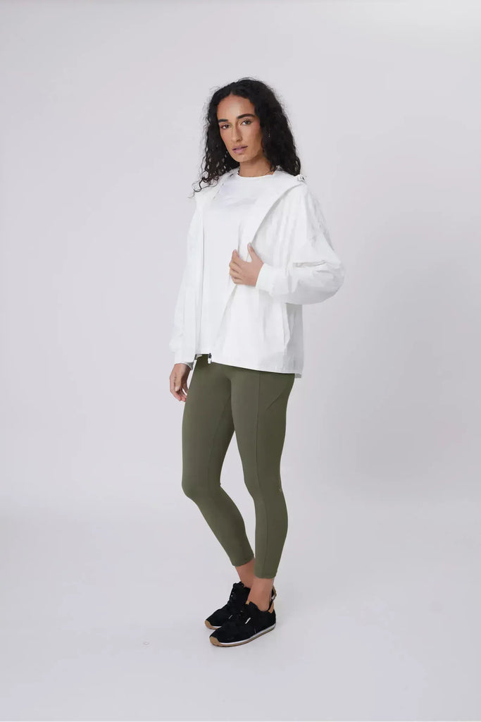 Person wearing a white windbreaker on a plain background. Motion Windbreaker in white from Marlow.