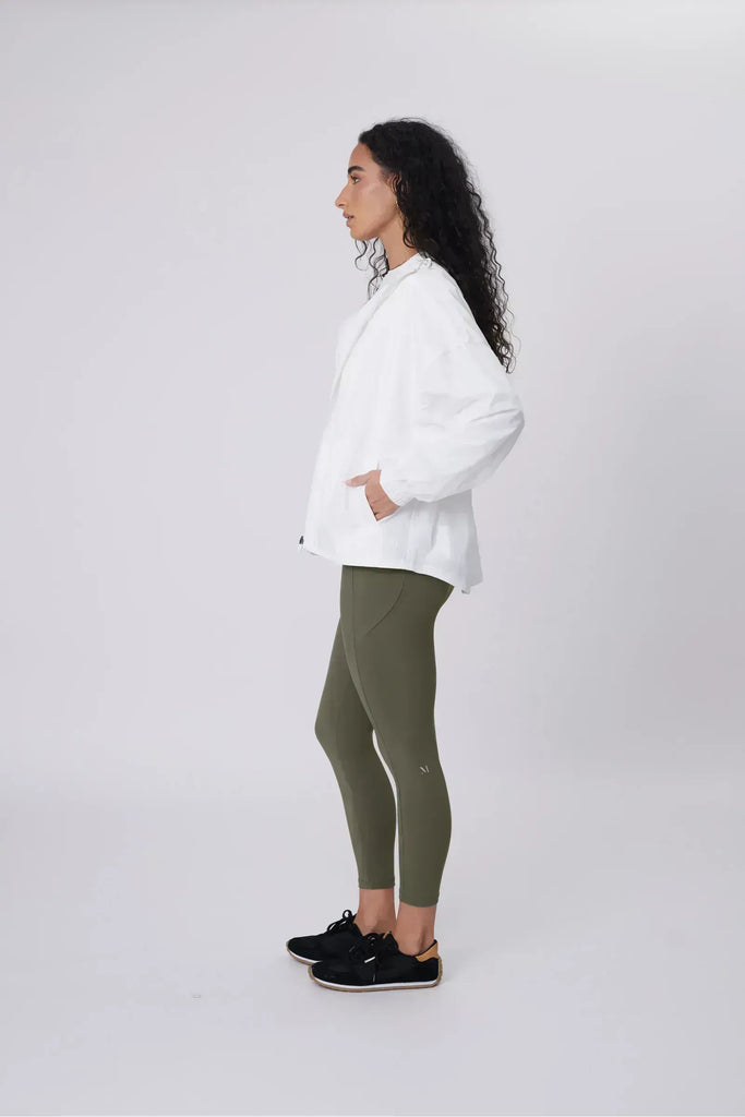 Person wearing a white windbreaker on a plain background. Motion Windbreaker in white from Marlow.