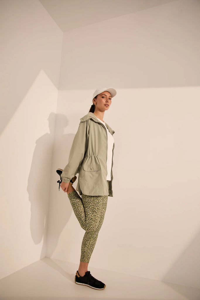 Woman wearing a white t-shirt and green patterned leggings on a plain background. Marlow Pace 7.8 Legging in Green Willow Print.
