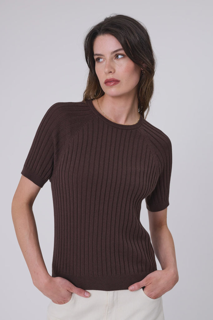 Woman wearing a chocolate brown knit tee and ecru denim on a grey background. Marlow Wisp knit Tee Carob.