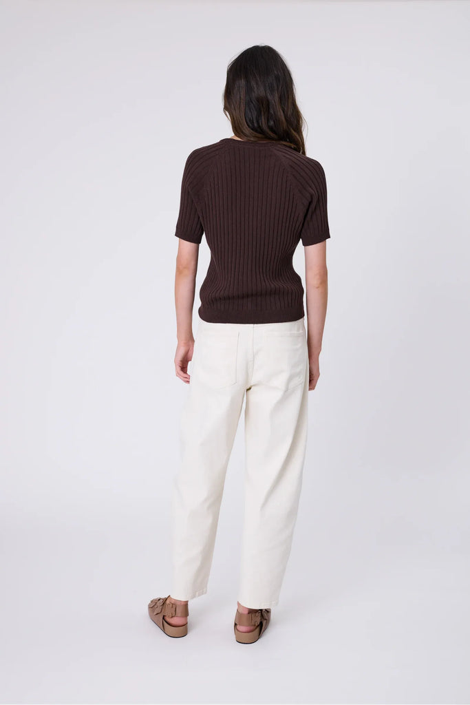 Woman wearing a chocolate brown knit tee and ecru jean on a grey background. Marlow Wisp knit Tee Carob.