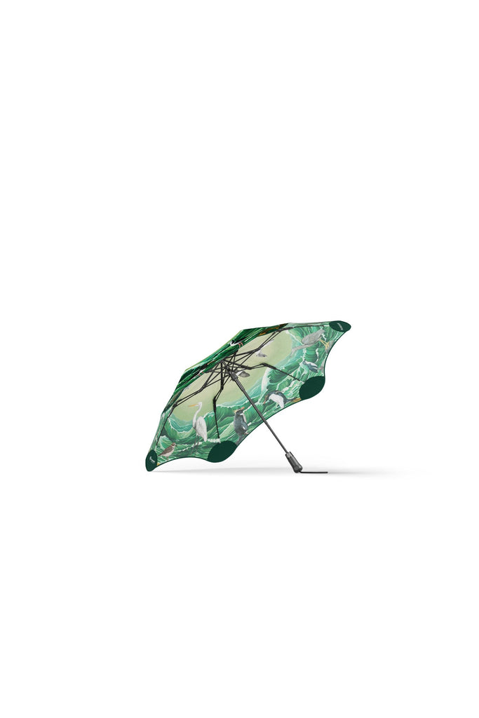 Blunt x Forest & Bird 2025 Limited Edition Metro Umbrella. Featuring artwork by Kiwi artist Tanya Wolfkamp. Showcasing Aotearoa's native sea and shore birds.  The image shows the underside of the canopy, through which the viewer catches a glimpse of the exterior canopy  featuring 16 native NZ sea and shore birds, and Aotearoa New Zealand’s coastal wildlife in a swirling, ocean-inspired design.