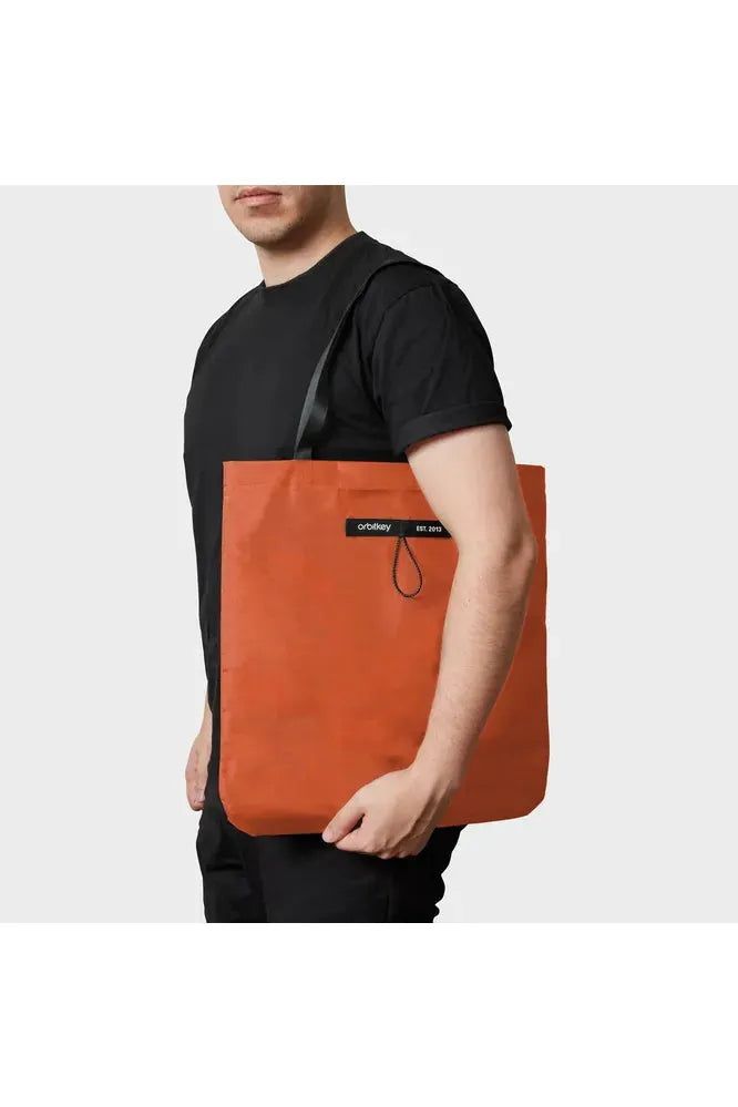 Orbitkey_Foldable_Tote_Bag_Limited_Edition_Tangerine_Colour._Image_shows_tote_being_carried_over_a_Male_shoulder._Crisp_Home_Wear