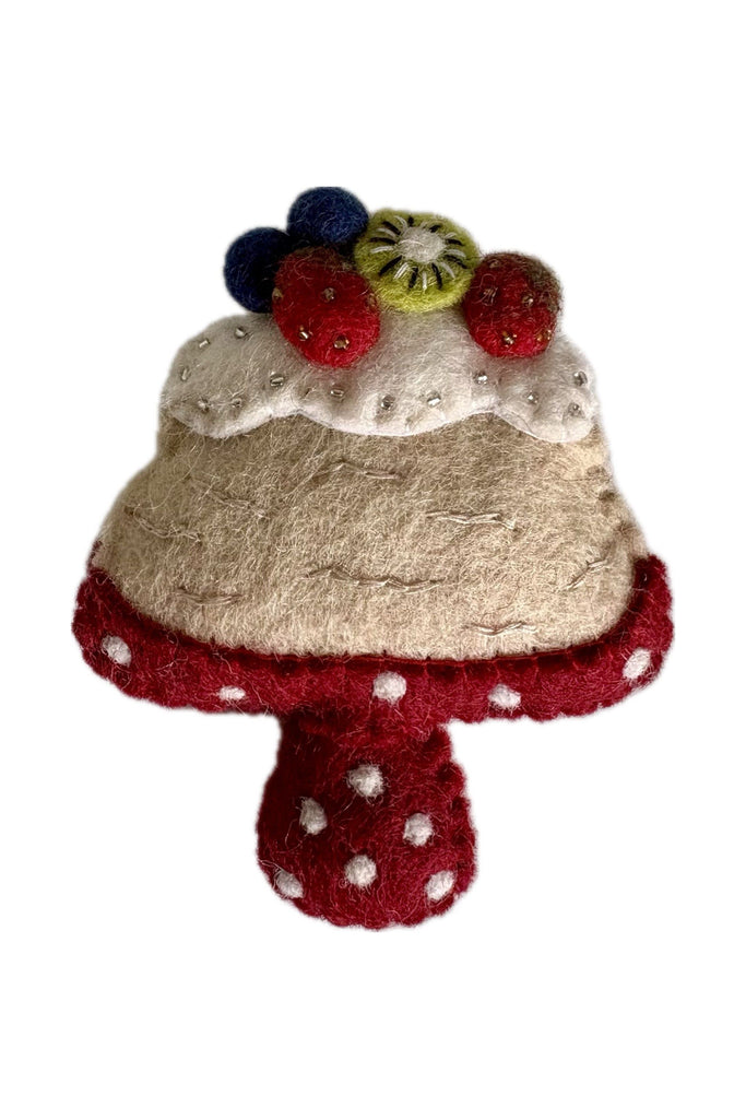 Pashom International Hanging Felted Christmas Decoration, Pavlova, topped with cream and fruit, sitting atop a red and white spotted cake stand ona white background.