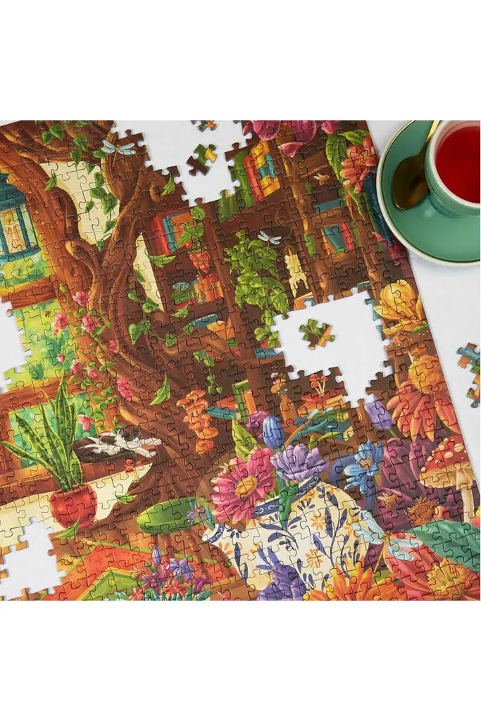 Piece House and Zoe Gillett's collaboration jigsaw puzzle titled 'Petals & Pages' features an image of a room filled with books and plants beside a cup of tea.