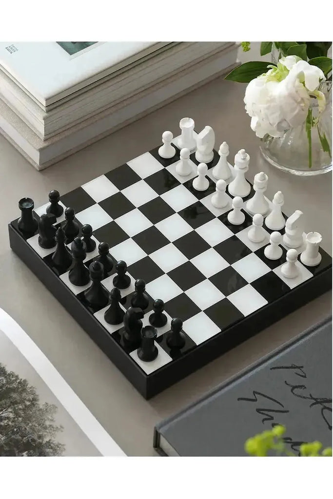 Printworks Art of Chess, Chessboard with black and white pieces on a table with books and flowers.