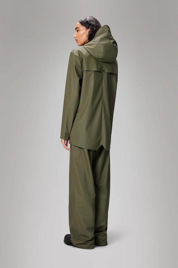Person wearing a green Rains raincoat in Marsh colourway on a grey background