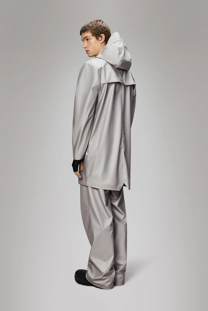 Man wearing a Rains Nimbus long light grey metallic raincoat on a plain background
