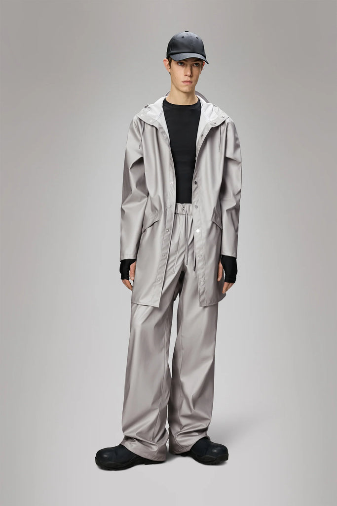 Man wearing a Rains Nimbus long light grey metallic raincoat on a plain background