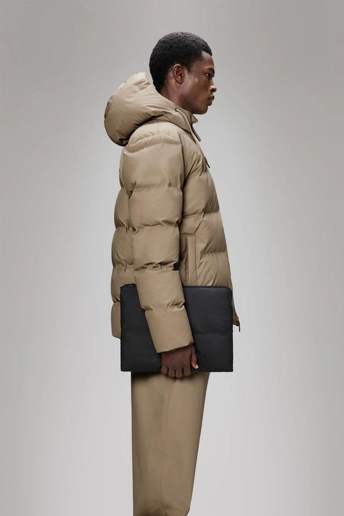 Person holding a Rains Black Puffer Laptop Cover on a light gray background