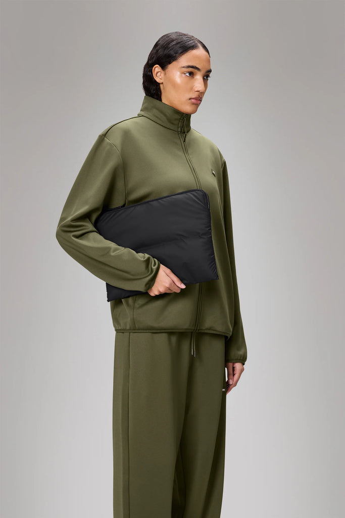 Person holding a Rains Black Puffer Laptop Cover on a light gray background