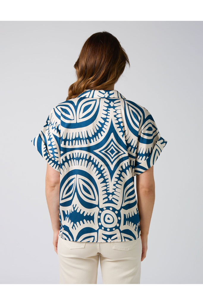 Woman wearing a blue and white patterned shirt on a plain background. Stella and Gemma Melanie Blouse in the Bellinis on Bondi Print 