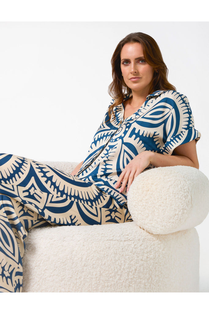 Woman wearing a blue and white patterned outfit sitting on a white chair.