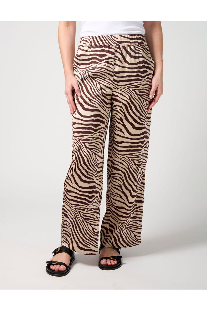 Woman wearing a zebra print pant and white tee on a white background. Stella and Gemma Jenna Pant in Merlot Zebra.