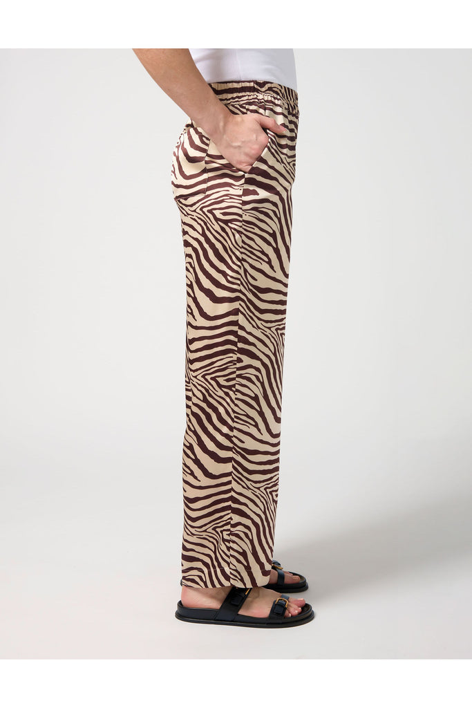 Woman wearing a zebra print pant and white tee on a white background. Stella and Gemma Jenna Pant in Merlot Zebra.
