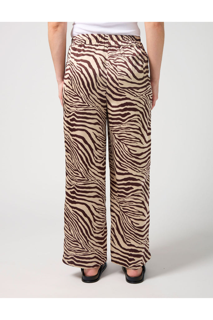 Woman wearing a zebra print pant and white tee on a white background. Stella and Gemma Jenna Pant in Merlot Zebra.