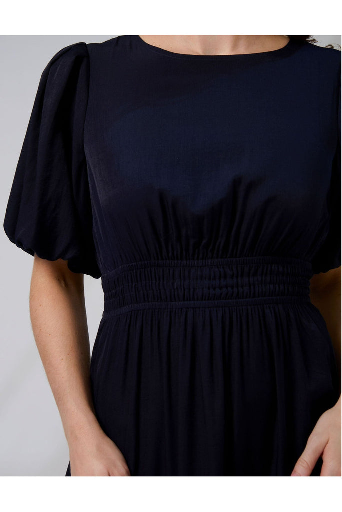 Woman wearing a navy blue Sabrina dress from New Zealad Label Stella and Gemma on a white background front close up view
