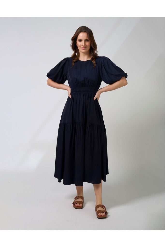Woman wearing a navy blue Sabrina dress from New Zealad Label Stella and Gemma on a white background front view