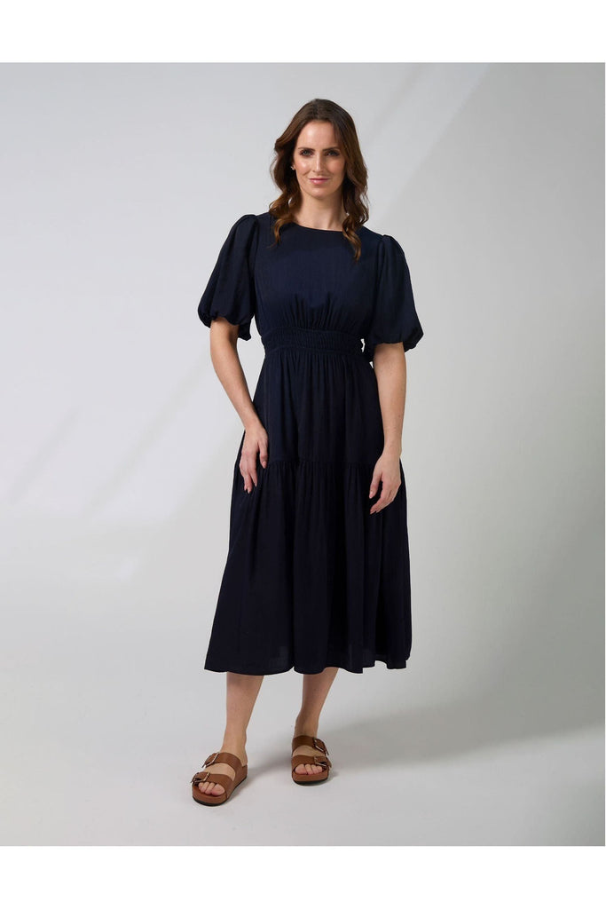 Woman wearing a navy blue Sabrina dress from New Zealad Label Stella and Gemma on a white background front view