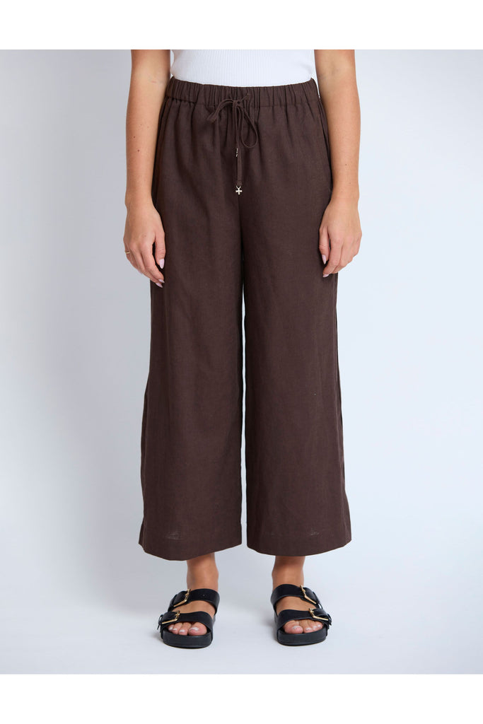 Person wearing brown wide-leg pants on a plain background