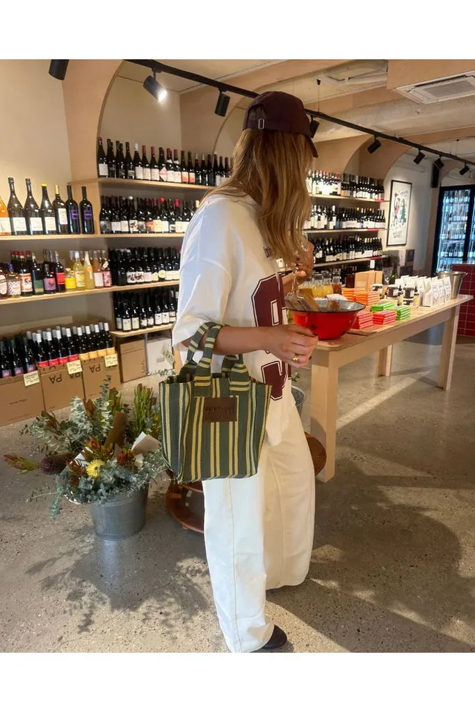 Person shopping in a wine store with a striped bag