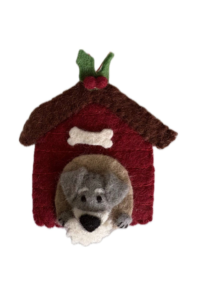 Pashom Felted Schnauzer dog ornament inside a kennel with their face poking through the doorway.  Kennel has a sprig of holly on top. 