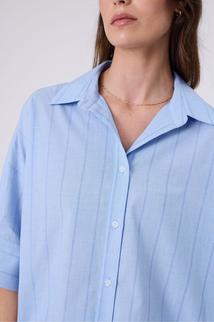 Woman wearing a light blue striped shirt  on a white background. Marlow Shoreline Shirt.