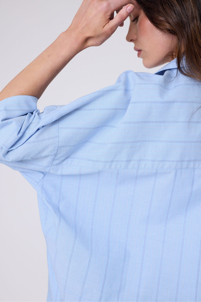 Woman wearing a light blue striped shirt on a white background. Marlow Shoreline Shirt.