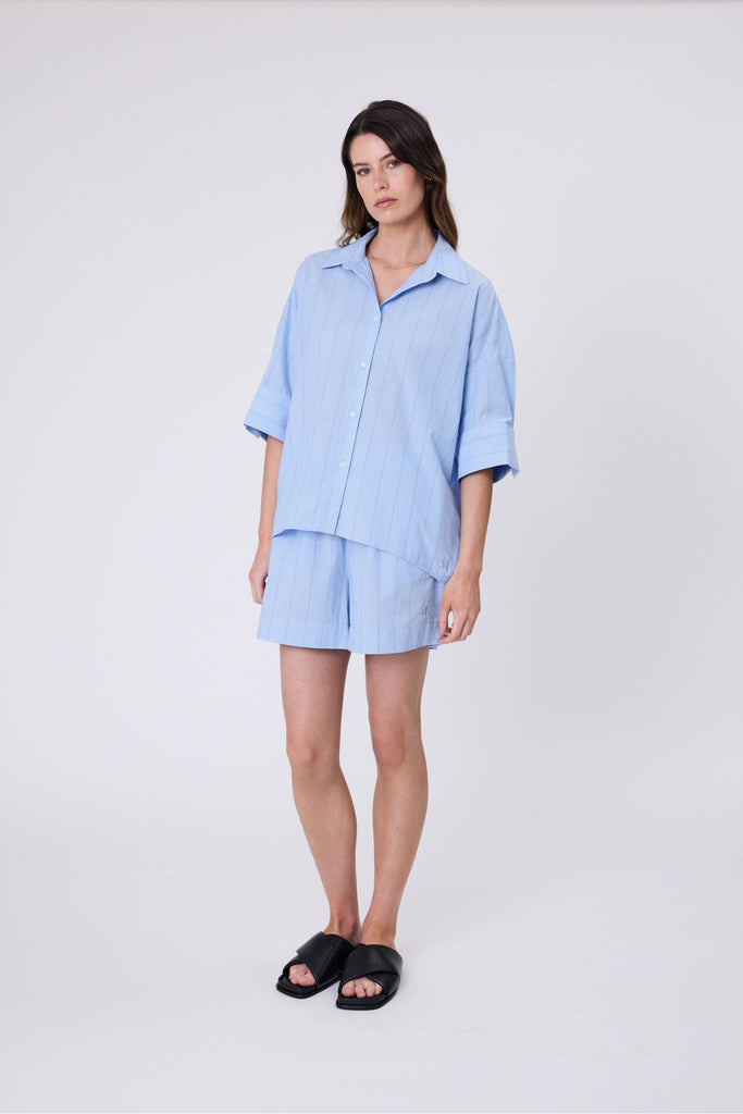 Woman wearing a light blue striped matching shirt and shorts on a white background