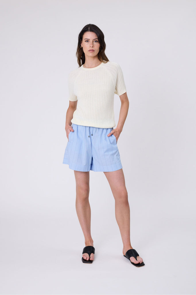 Woman wearing a light blue striped shorts with a tee on a white background