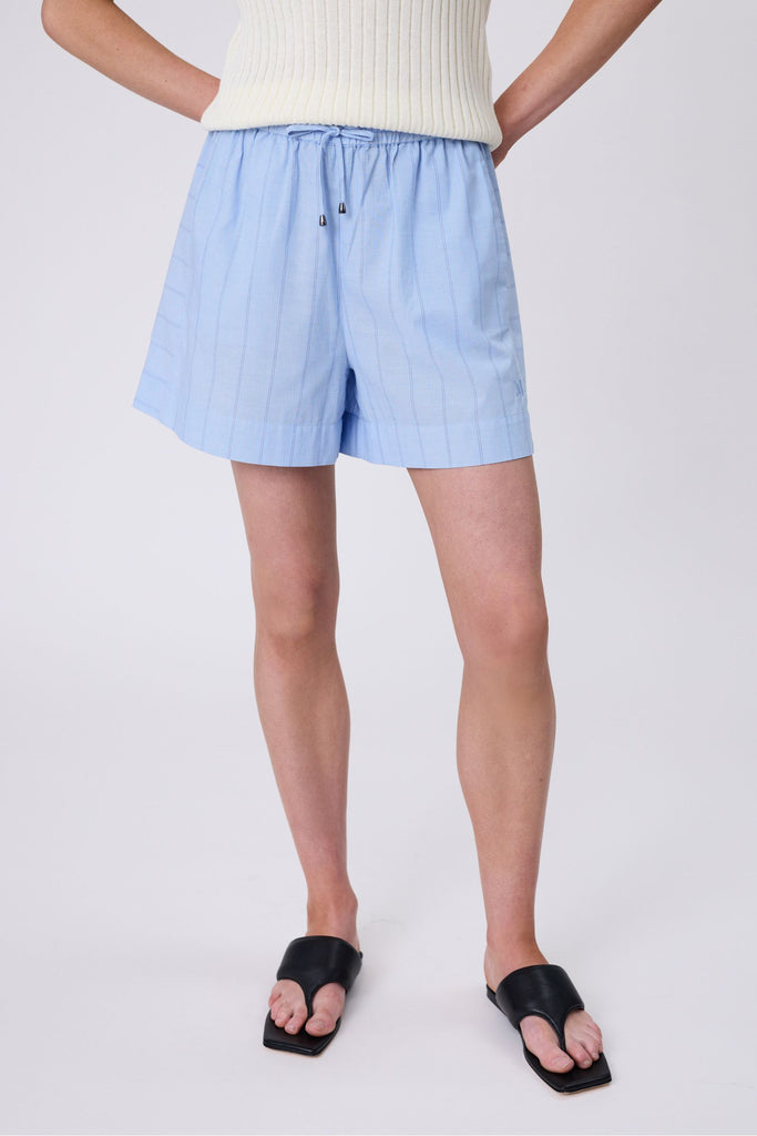 Person wearing light blue striped shorts on a white background