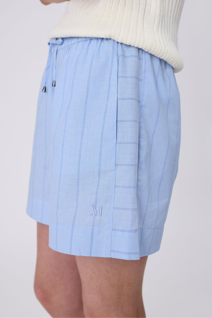 Woman wearing light blue striped shorts on a white background